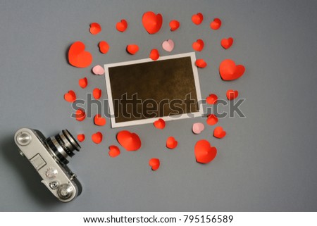 Vintage retro camera on on grey background with blanks photo to placed your pictures and red hearts . Valentines day background. Top view.