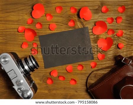Vintage retro camera on wooden table background with blanks photo to placed your pictures and red hearts . Valentines day background. Top view