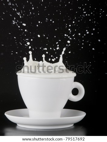 Milk splashing out of cup isolated over black  background