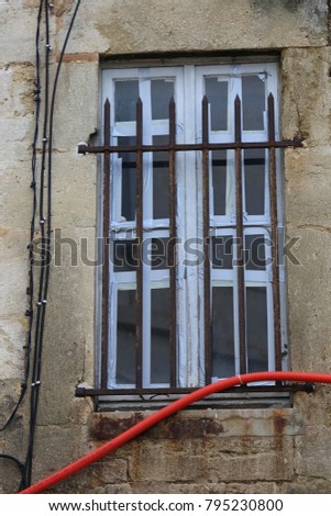 View of an old wooden broken window in Montpellier city France. Stone grey facade of the ancient building and rectangular frame of the window. Glass damaged and house abandoned.  Vintage picture .