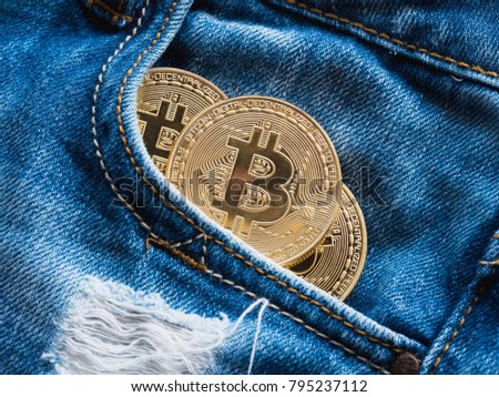 Tree bitcoins in front blue jeans pocket with hole