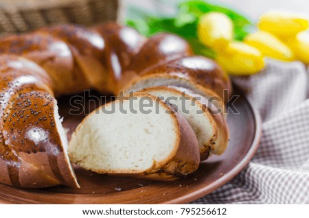 Easter sweet bread and yellow tulips. Traditional wicker homemade bread. Sweet wheat sliced bun on a wooden background. Rustic style.