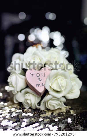 Image of Valentine's day or wedding composition with small pink wooden heart and bouquet of white roses 