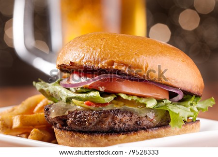 gourmet cheeseburger with mug of beer in background