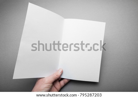 An empty cover of a brochure on a gray background in the hand, a design of a menu or magazine.