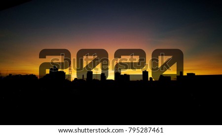 year 2020 on sunset sunrise behind town in silhouette yellow sky background
