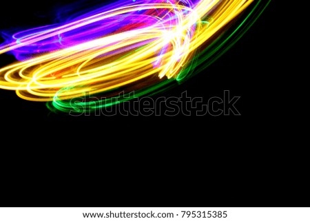 Multi color gold, blue, red and green light painting, long exposure photography, stream of light, against a clean black background