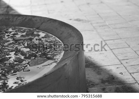 Black and white street photography of stone fountain full of broken ice, picture full of contrasts