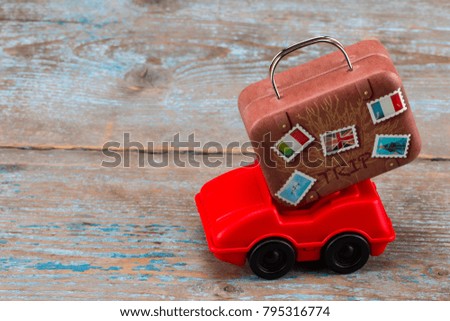 red toy car with suitcases on a wooden background. Travel concept. With copy space.
