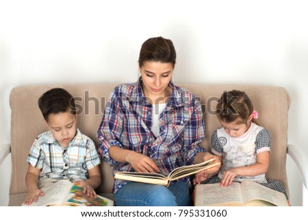 Mother is engaged with children. Mother with small children read books. 