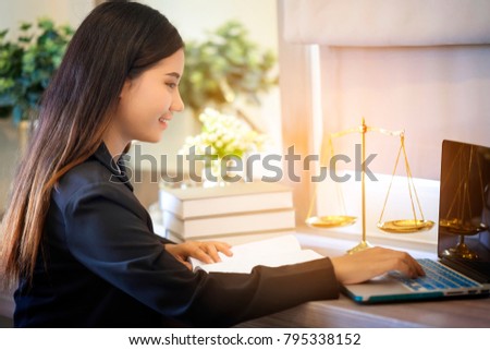Young lawyer woman work on laptop with scale of justice and law textbook on table in office, feel happiness when prepare an advice for courtroom. Notary student study on legal law. Layer concept.
 Royalty-Free Stock Photo #795338152