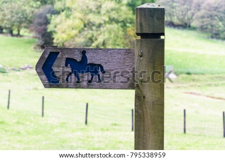 Wooden sign with picture of horse and rider to indicate public bridleway, United Kingdom