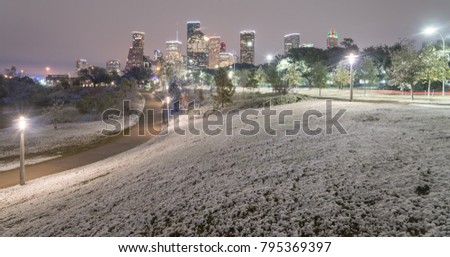 Panorama downtown Houston with big and fluffy snowflakes fell on meadow grass. Park lawn, curved bike pathway at Eleanor Tinsley Park modern skylines in background. Snow is extremely rarely here