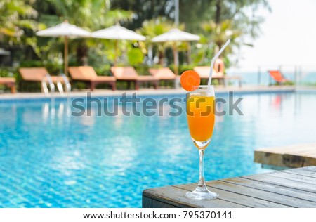 Orange juice with carrot slice in cocktail glass on wooden table at outdoor swimming pool, summer tropical holiday concept Royalty-Free Stock Photo #795370141