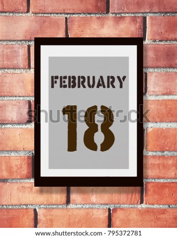 February 18th. 8 February calendar on the wood photo frame with brown brick background. Winter day.