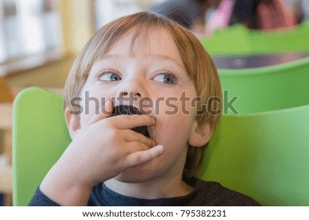 adorable toddler boy eating chocolate sandwich cookie for snack
