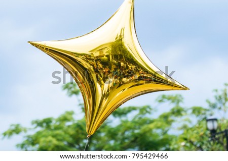 
Golden star balloon floating in the sky.