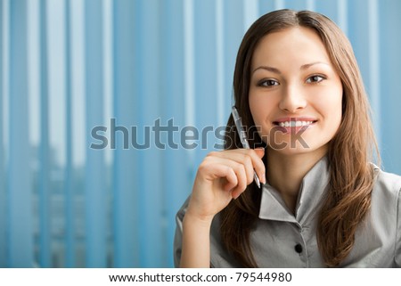 Portrait of beautiful young happy smiling businesswoman with pen at office