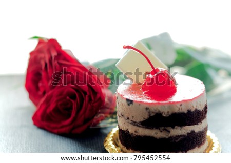 Bakery cream,chocolate with topping a cherry and Red Rose on the table. Tiny  square white chocolate bar blank space for filling texs. symbol of love. Valentine's Day concept.selective focus of image.