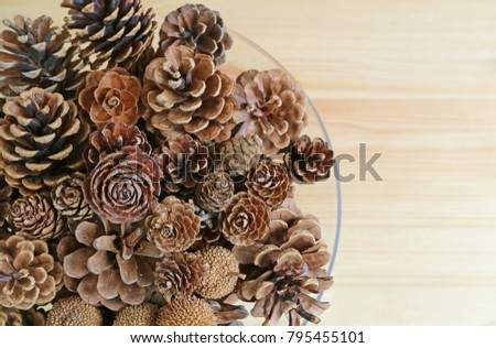 Top view of various type and size of natural dry pine cones in a glass bowl, with free space for design or text 