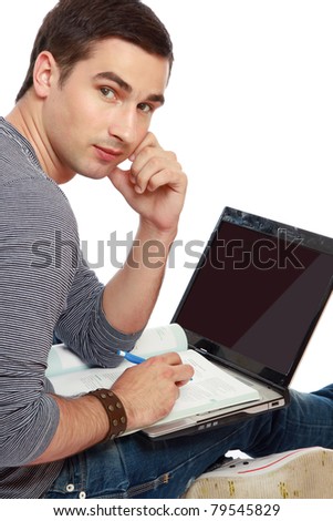 A full-length portrait of a young smiling guy sitting on the floor with a laptop, studying, isolated on white