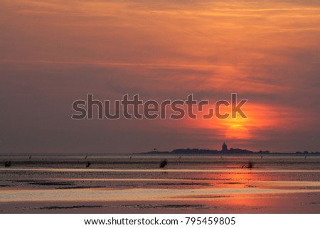 summer sunset at the watt flat with silhouette of an island and lighthouse