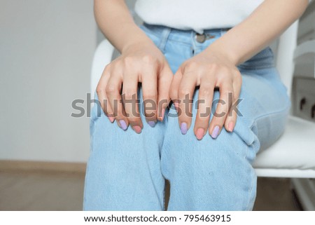 Close Up Nails Manicure. Beautiful Woman with Pink and Violet Pastel Nail Polish. Sitting on a White Chair Background Great for Any Use.