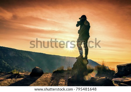photographer man shooting mountain orange light at sunset.
