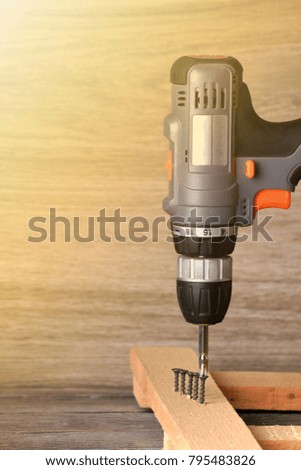 Close up Electric drill on wooden table background and copy space. 
Hammer drill or screwdriver, Electric cordless hand drill on wooden. maintenance home concept.
Screwdriver on a wooden background wi