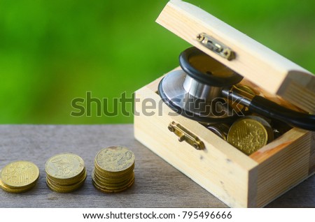 Image of Golden coins stacked on treasure chest with stethescope, on wooden rustic background. medical concept
