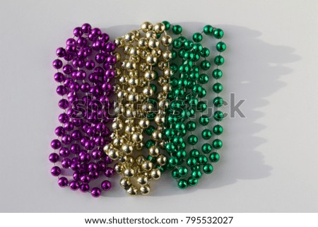 The three traditional colors in the beaded necklaces of Mardi Gras. Purple represents Justice, green represents Faith, and gold represents power.