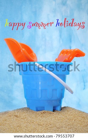 a castle bucket with shovels and rake with the sentence happy summer holidays