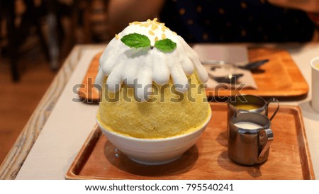 Bingsu mango in white cup. Have white condensed milk and mango juice for pour. Popular in summer.