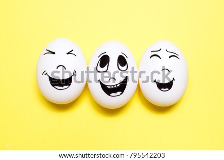 Three eggs with drawn laughing cartoon faces on yellow background. Friends concept
