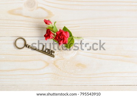 Valentine's day / endless love or special occasion concept : Top or above view of a love key and red roses on wood texture background with copy space. Depicts love passion for romantic couple.