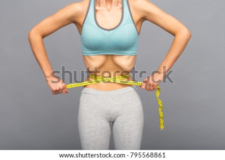 Dieting, anorexia. Thin woman showing her narrow waist using measure tape.