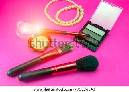 Cosmetics for professionals placed on a pink background. There is an orange light in the picture.