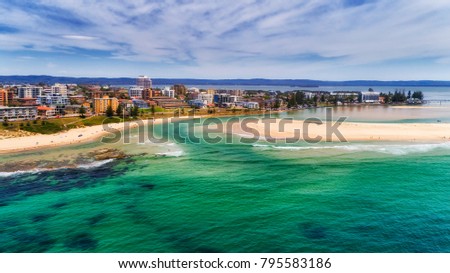 Small regional town at the entrance of Tuggerah lake to Pacific ocean on Australian Central coast. Aerial view of town waterfront along canal and distant bridge. Royalty-Free Stock Photo #795583186