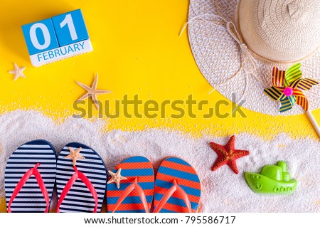 February 1st. Image of february 1 calendar with summer beach accessories and traveler outfit on background. Winter like Summer vacation concept