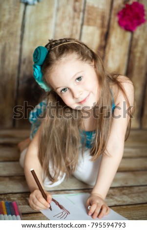 Cute girl drawing with felt-tip pens in an easter decorated studio with wooden background