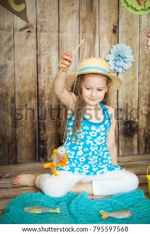 Cute girl fishing felted fishes in an easter decorated studio with wooden background
