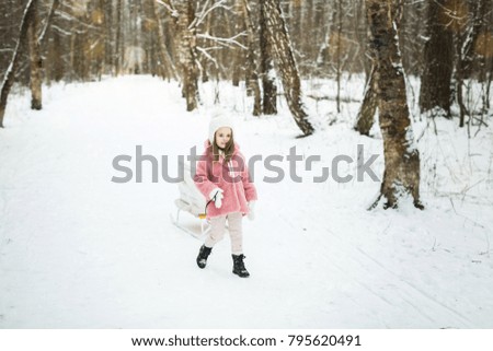 little girl is carrying a sledge with gift boxes