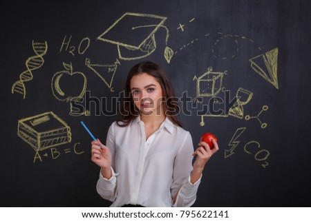 A girl holding a red apple, standing near a board with images of signs of ideas, science and knowledge.