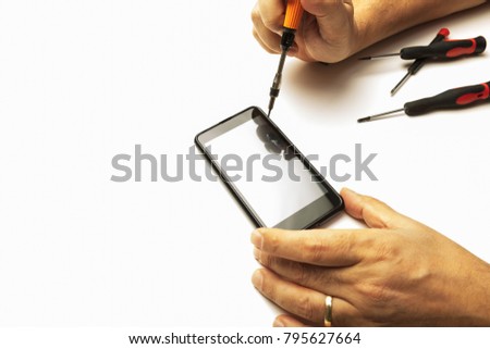 Man using precision screwdrivers on his smartphone in a close up view of his hands in a concept of screen replacement, repairs and maintenance over white with copy space