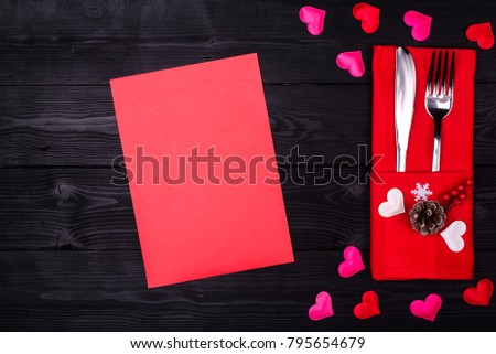 Valentines day table setting with fork, knife and red dinner napkin on black background, Top view, with copy space for your text. Background for the menu to Valentine's day or wedding.