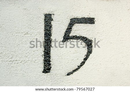 Number fifteen painted on the wall outside a house in London.