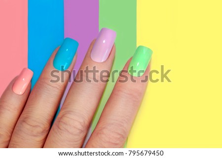 Multi-colored pastel manicure combined tone on tone with a striped background.Nail art. Royalty-Free Stock Photo #795679450