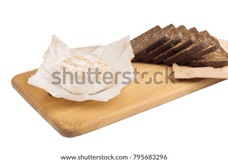 Slices of black rye bread with sunflower seeds lie on a wooden board next to cheese. Time for bite
