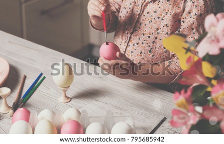 Little girl is painting eggs. easter concept.