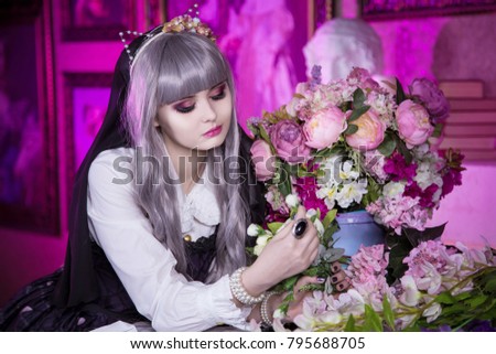 A beautiful woman in a doll dress, in a gray wig stands at a bouquet with flowers in the background of pictures. Kawai Lolita. Japanese street fashion.